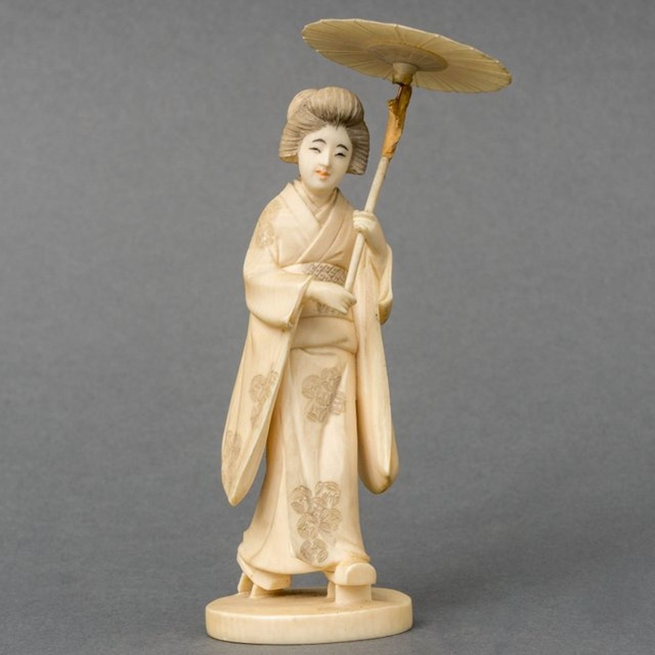 Japanse School, 19e eeuw | Okimono of a woman in a kimono holding a parasol, ivory, 13.0 cm